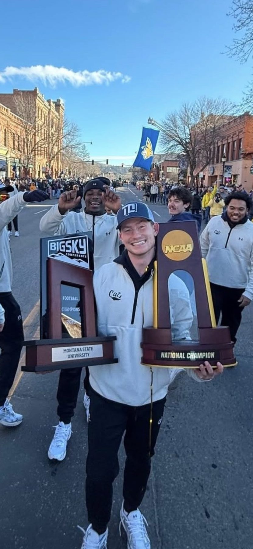 Bobcats carry the Big Sky and NCAA National Champion trophies down Main Street in Bozeman