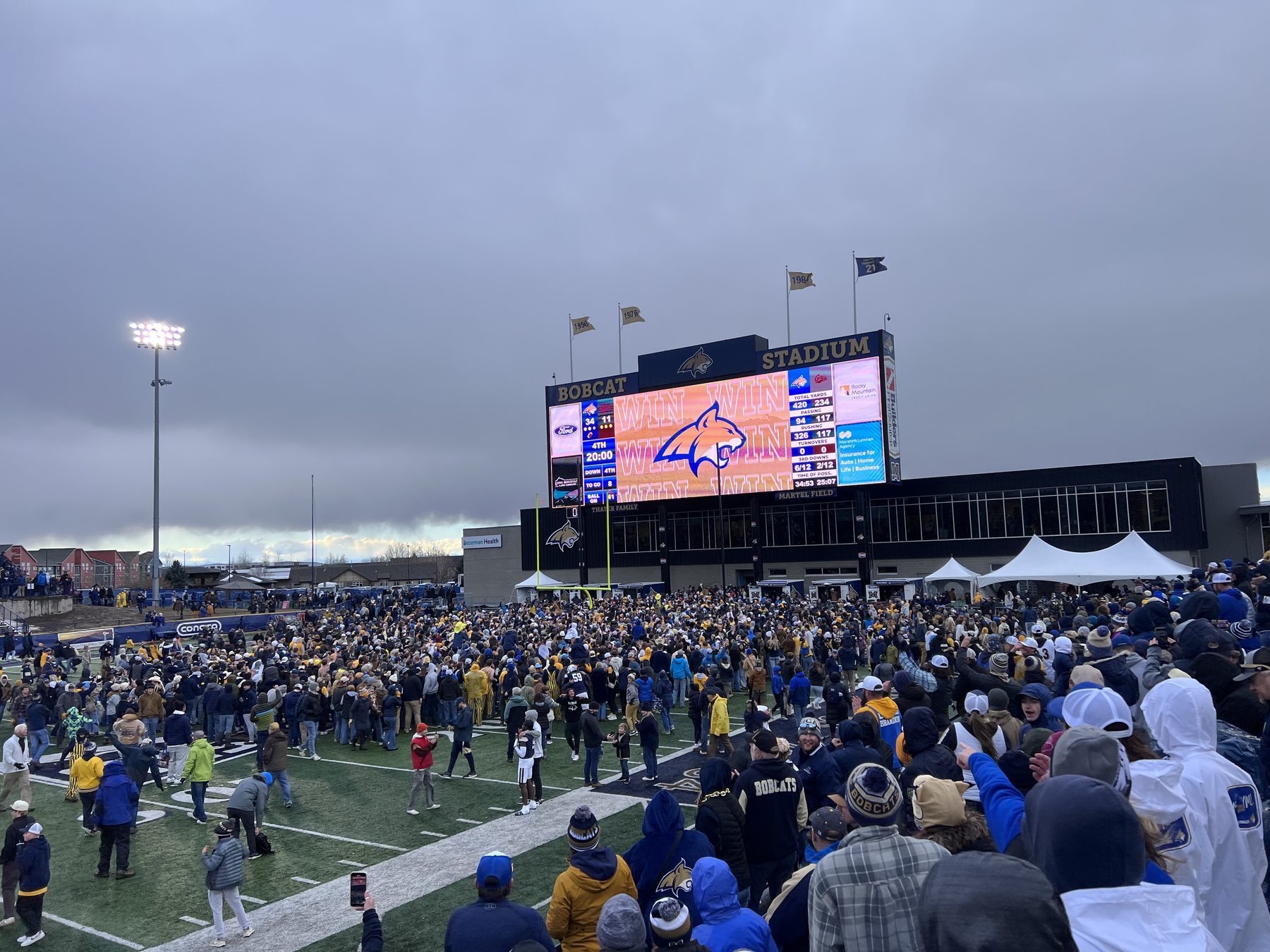 The Bobcat Stadium videoboard flashes WIN as Montana State fans flood the field after beating Montana 34-11
