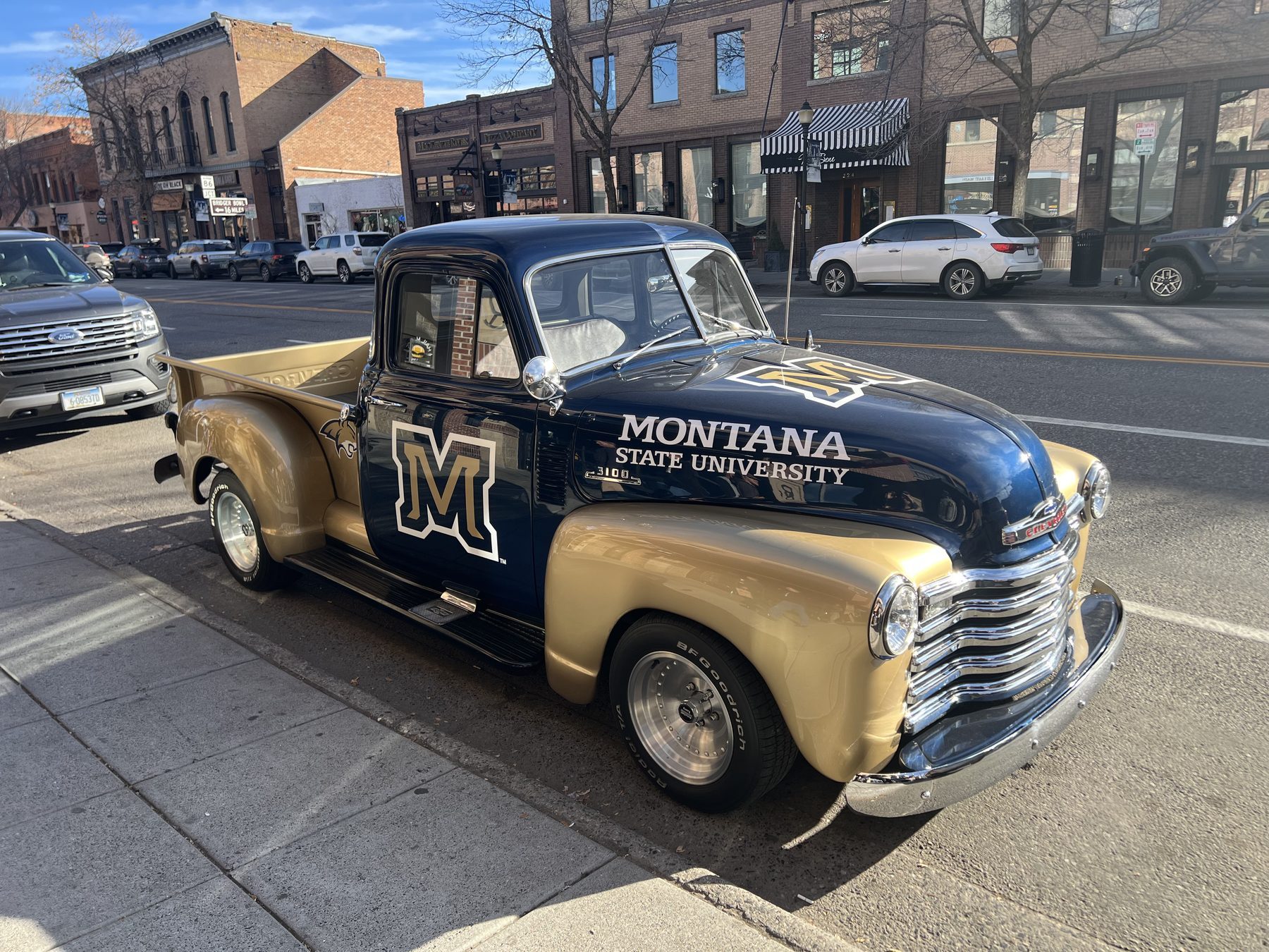 A vintage Chevy pickup painted in Montana State navy and gold parked on Main Street in downtown Bozeman